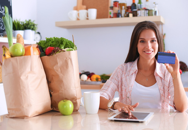 Smiling woman online shopping using tablet and credit card in kitchen - Photo, Image