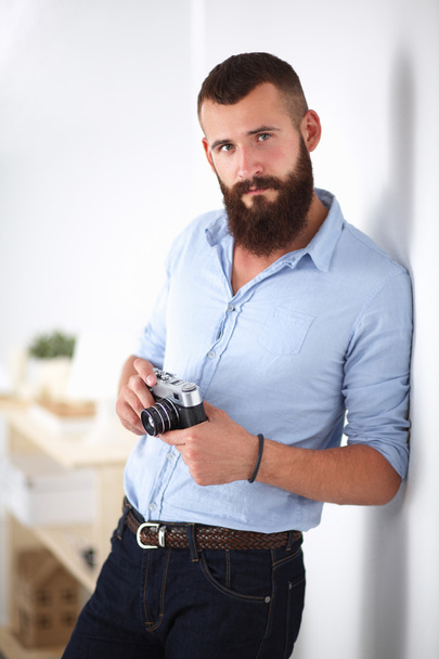 Young beard man holding a camera while standing against white background - Фото, зображення