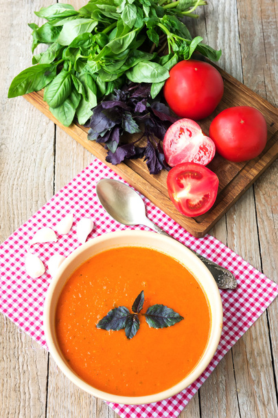 Sopa de tomate fresco con albahaca y tomates sobre mesa de madera
 - Foto, imagen