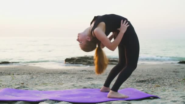 young female practices yoga on the beach slow motion - Footage, Video