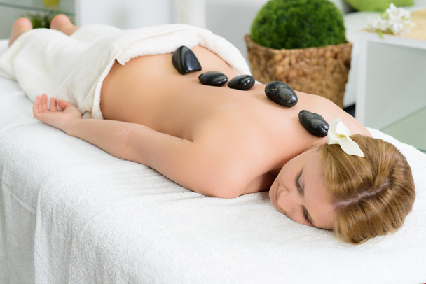 Beautiful woman bekoming hot stone massage in spa - Foto, immagini