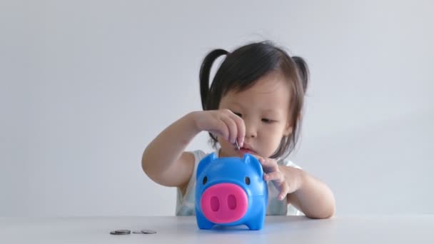 Mädchen legt Geld in Sparschwein - Filmmaterial, Video
