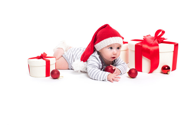 Cute baby in a red New Year's cap with a smile on his face lying - Fotografie, Obrázek