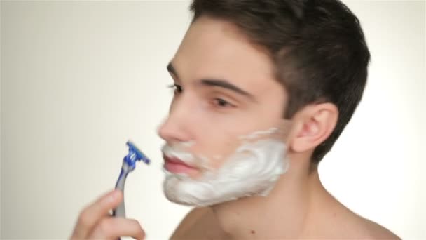 ein hübscher junger Mann rasiert sich - Filmmaterial, Video