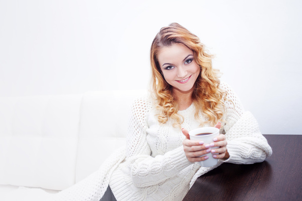 Young woman at home drinking hot coffee, wrapped in a scarf,  white background, place for your text - Zdjęcie, obraz