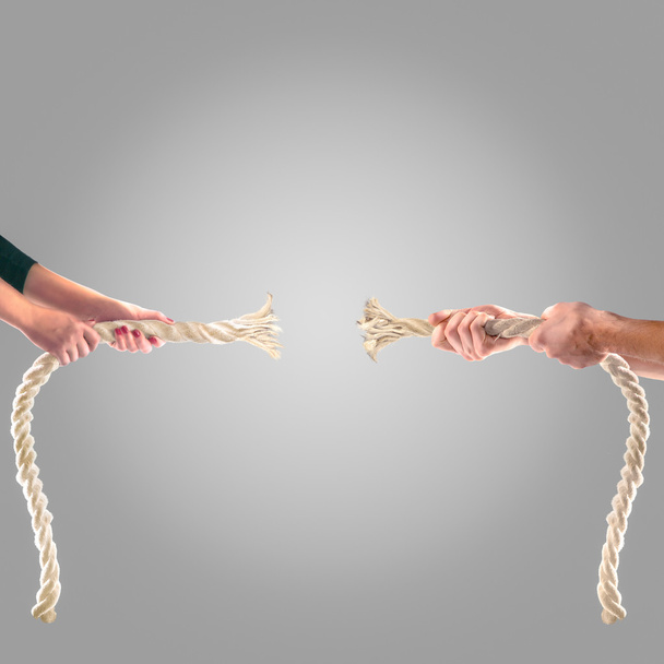 Hands of people pulling the rope on a gray background.  Competition concept - Fotoğraf, Görsel
