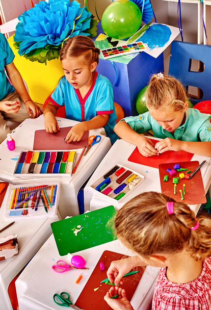 Grupa dzieci formowane z plasteliny tabeli w przedszkolu . - Zdjęcie, obraz