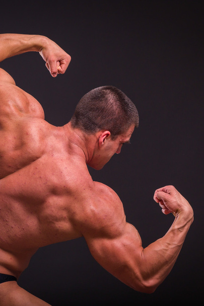 bodybuilder professionnel montre son corps sur un fond sombre
 - Photo, image