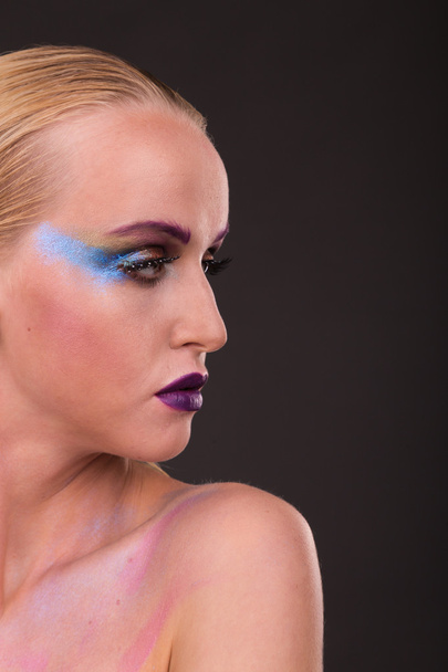 Beautiful model with art makeup on a dark background - 写真・画像