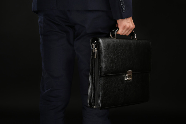 Elegant man in suit with briefcase on dark background - Zdjęcie, obraz