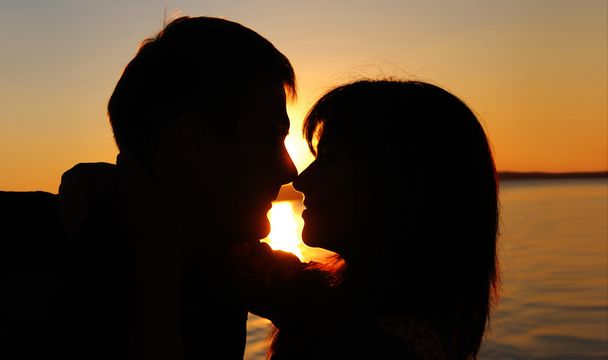 romantisch paar kussen bij zonsondergang - Foto, afbeelding