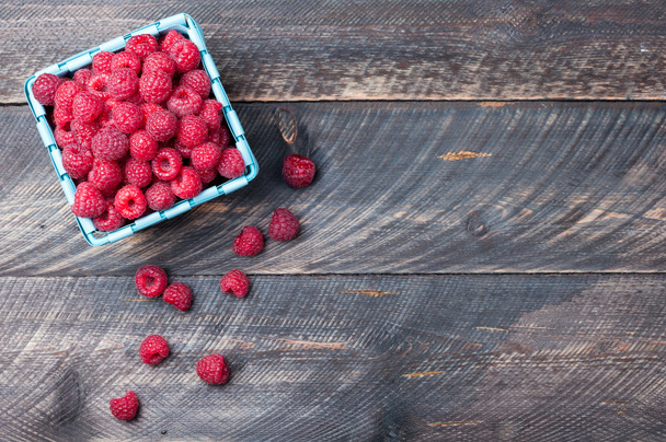 Raspberries in a basket on old wooden background. Rustic style - 写真・画像