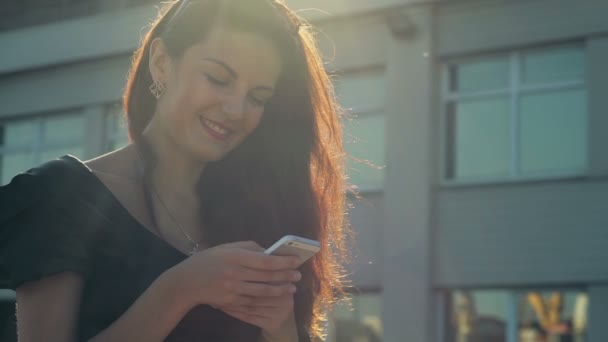 Elegante Dame nutzt Smartphone und lächelt in Zeitlupe auf der Straße - Filmmaterial, Video