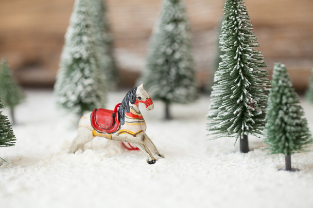 Різдвяна листівка - мініатюрна новорічна ялинка та конячка-качалка на снігу - зима
 - Фото, зображення
