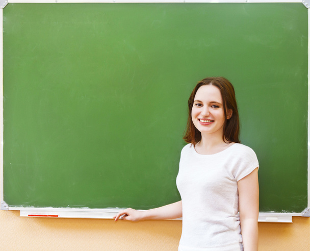 Студентська дівчина стоїть біля чистої дошки в класі
 - Фото, зображення