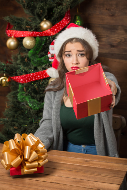 Beautiful girl demonstrating empty box of present near New Year tree - Zdjęcie, obraz