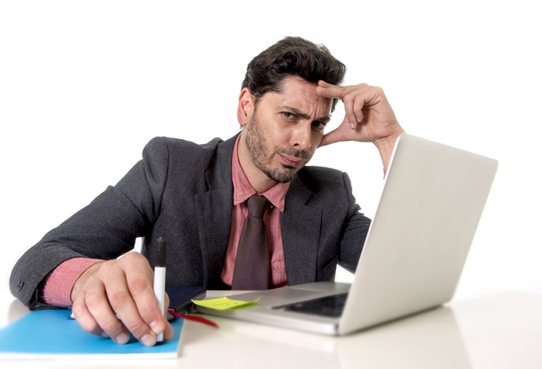 attraente uomo d'affari alla scrivania dell'ufficio che lavora sul computer portatile cercando stanco e occupato
 - Foto, immagini