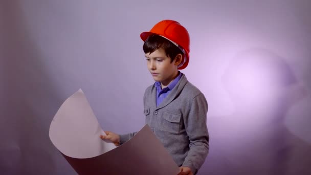 Teen boy builder in helmet holding building plan documents - Metraje, vídeo