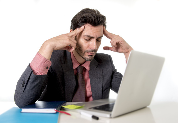 giovane uomo d'affari attraente seduto alla scrivania dell'ufficio che lavora sul computer portatile che soffre di mal di testa
 - Foto, immagini