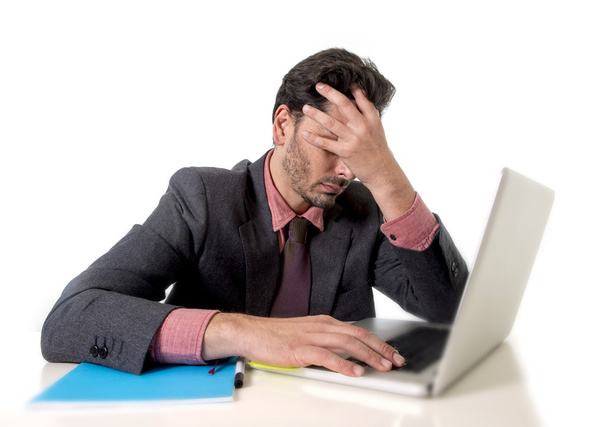 молодий бізнесмен, сидячи за офісним столом, працює на комп'ютерному ноутбуці, відчайдушно стурбований робочим стресом
 - Фото, зображення