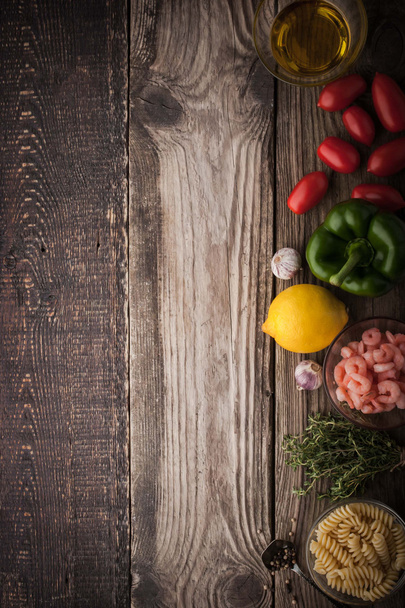 Vegetables with seasoning , shrimps and pasta on the wooden table vertical - Фото, зображення