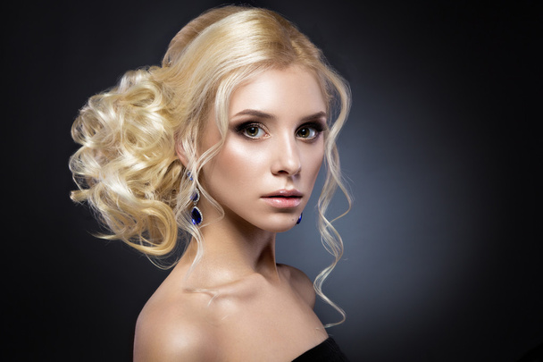 Beautiful blond girl in a black dress with evening haircut  form of waves and bright makeup. Beauty face. - Foto, afbeelding
