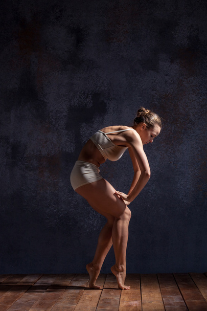 Молодая красивая танцовщица в бежевых купальниках танцует на сиреневом фоне
 - Фото, изображение