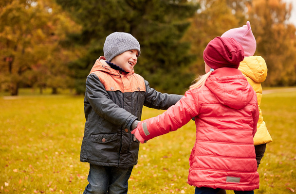 children holding hands and playing in autumn park - Φωτογραφία, εικόνα