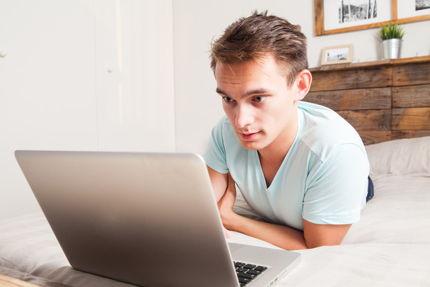 Młody student korzysta z laptopa w domu. - Zdjęcie, obraz