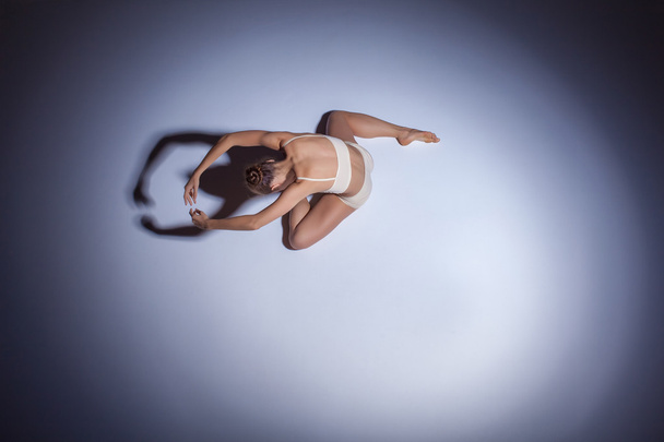 Young beautiful dancer in beige swimwear dancing on lilac background - Fotoğraf, Görsel