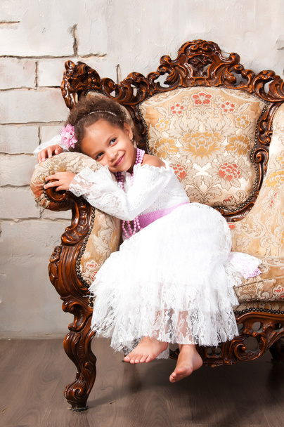 Close-up portrait smiling african  girl in a white lace dress on vintage chair - Photo, Image