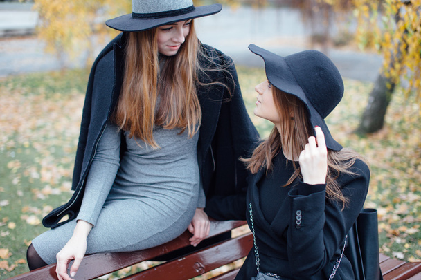 Two young girls sitting on the bench and posing to camera - Фото, изображение