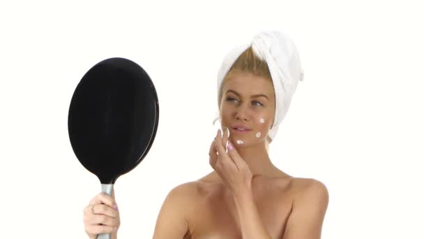 Smiling young woman applying face cream, bathroom - Кадри, відео