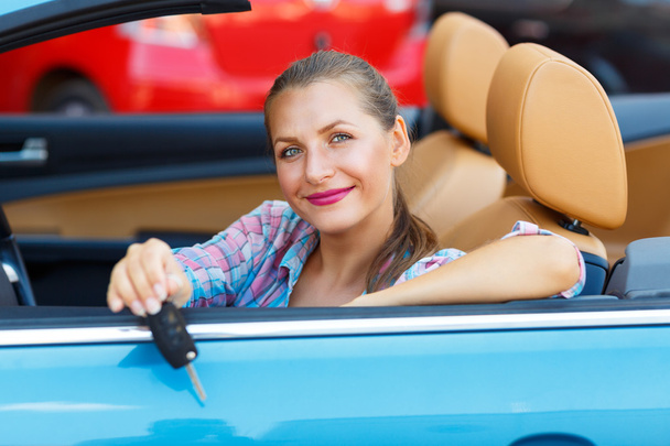 Jeune jolie femme assise dans une voiture décapotable avec les clés en
 - Photo, image