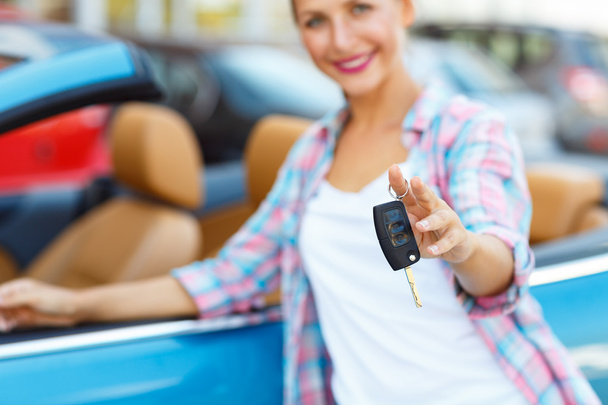 junge Frau steht neben einem Cabrio mit Schlüssel in der Hand - Foto, Bild