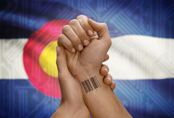 Barcode ID number on wrist of dark skinned person and USA states flags on background - Colorado - Fotoğraf, Görsel