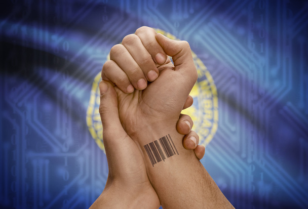 Barcode ID number on wrist of dark skinned person and USA states flags on background - Nebraska - Foto, Imagen
