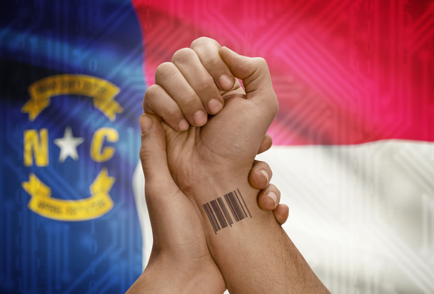 Barcode ID number on wrist of dark skinned person and USA states flags on background - North Carolina - Fotoğraf, Görsel