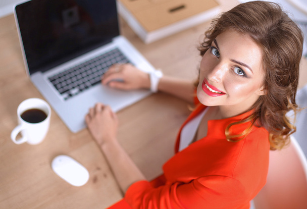 Attractive woman sitting at desk in office, working with laptop computer - Foto, afbeelding
