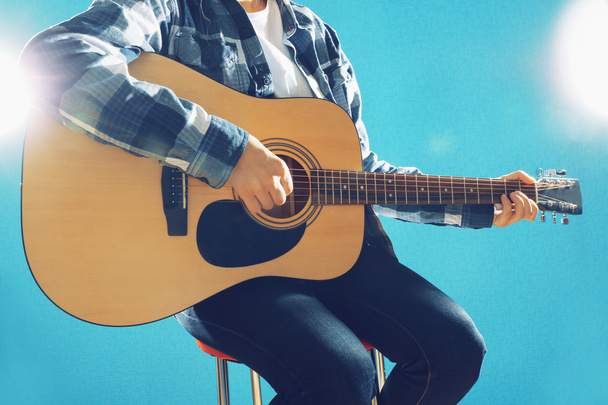 Musician plays guitar on blue background, close up - Foto, Imagem