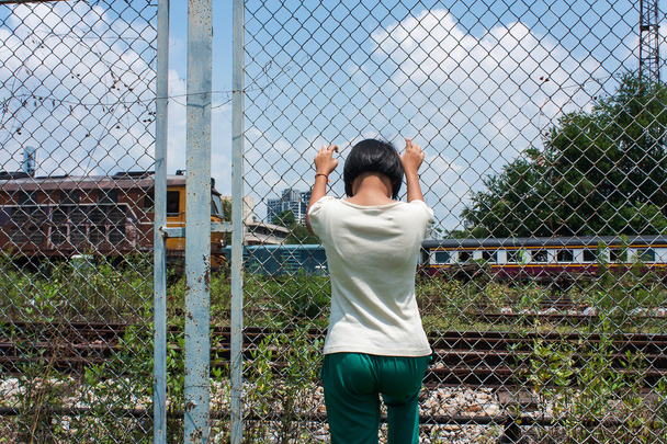 το ασιατικό κορίτσι λυπημένος μόνο χέρι κατέχουν φυλακή στο σιδηρόδρομο, σιδηροδρομικός σταθμός - Φωτογραφία, εικόνα