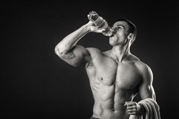 Мускулистый человек на темном фоне питьевой воды после тренировки
 - Фото, изображение