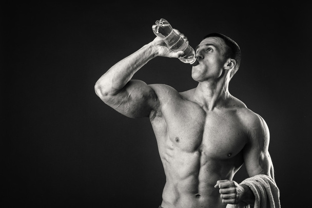 Lihaksikas mies tummalla pohjalla juomavesi harjoittelun jälkeen
 - Valokuva, kuva