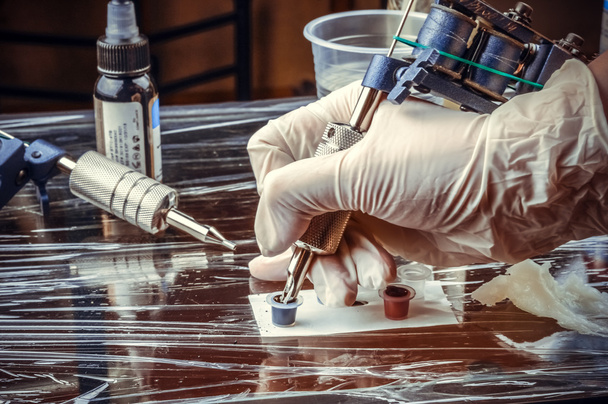 Татуировщик, показывающий процесс изготовления татуировки в тату-салоне
 - Фото, изображение