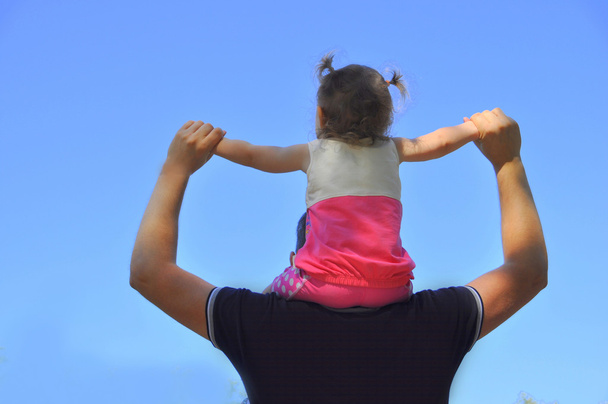 Little girl sitting on the shoulders of the  father - Photo, Image