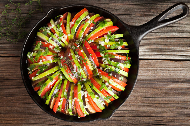 Традиционный сырой овощной рататуй в чугунной сковороде рецепт домашней здоровой вегетарианской пищи на винтажном деревянном столе фоне
 - Фото, изображение