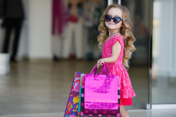 Little girl with shopping bags goes to the store - Photo, Image