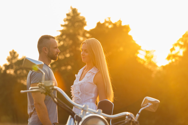 Мускулистый мужчина с красивой женщиной на мотоцикле посреди полевой дороги
 - Фото, изображение