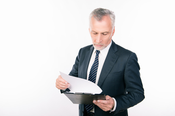 Old confident businessman reading information in a folder - 写真・画像