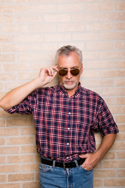 Homem velho bonito confiante segurando óculos de sol
  - Foto, Imagem